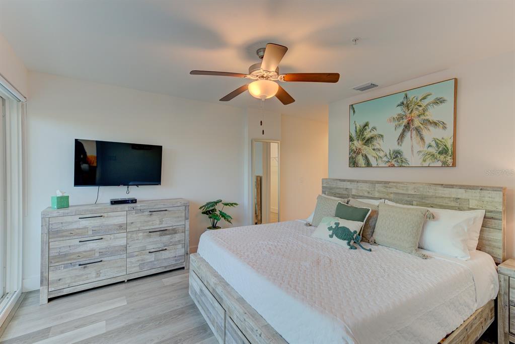 15305 1st Street East, Unit 202 Madeira Beach, FL 33708 - Photo 13 of 40 a bedroom with a bed and a flat screen tv