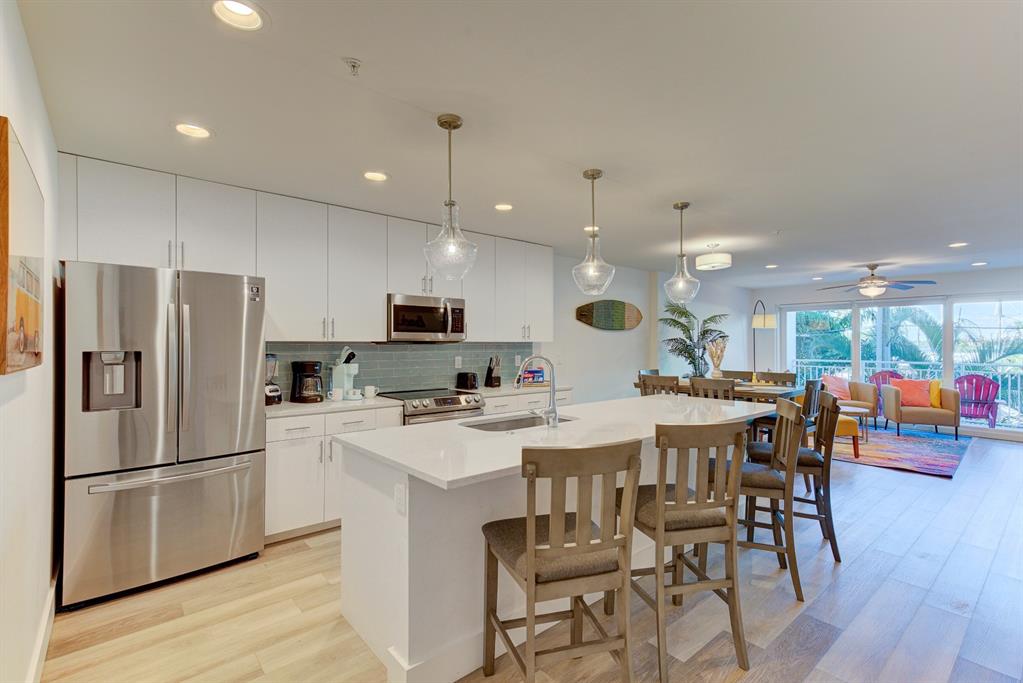 15305 1st Street East, Unit 202 Madeira Beach, FL 33708 - Photo 5 of 40 a kitchen with stainless steel appliances a dining table chairs stove and refrigerator