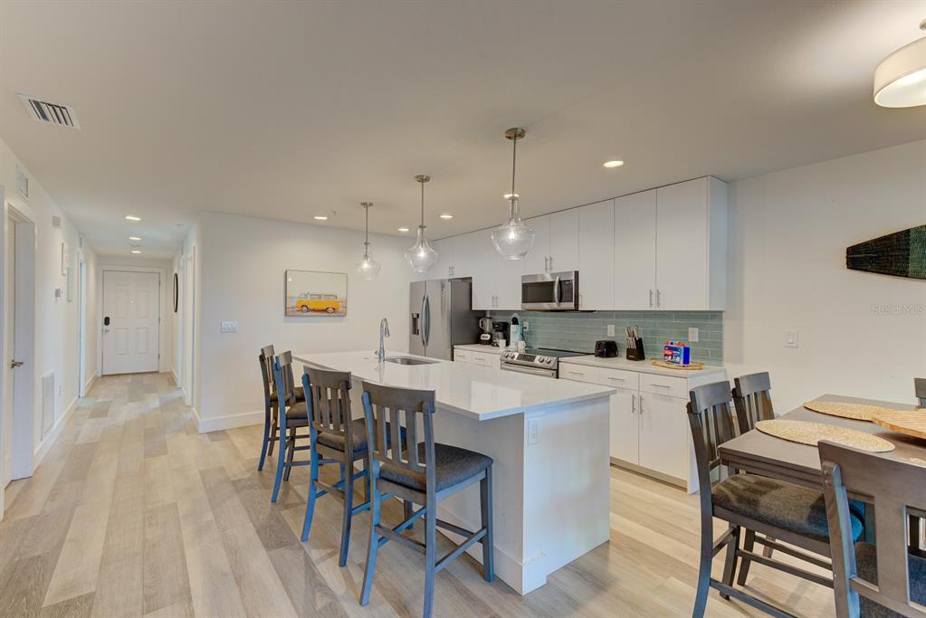 15305 1st Street East, Unit 202 Madeira Beach, FL 33708 - Photo 7 of 40 a kitchen with a dining table chairs wooden floor cabinets and appliances
