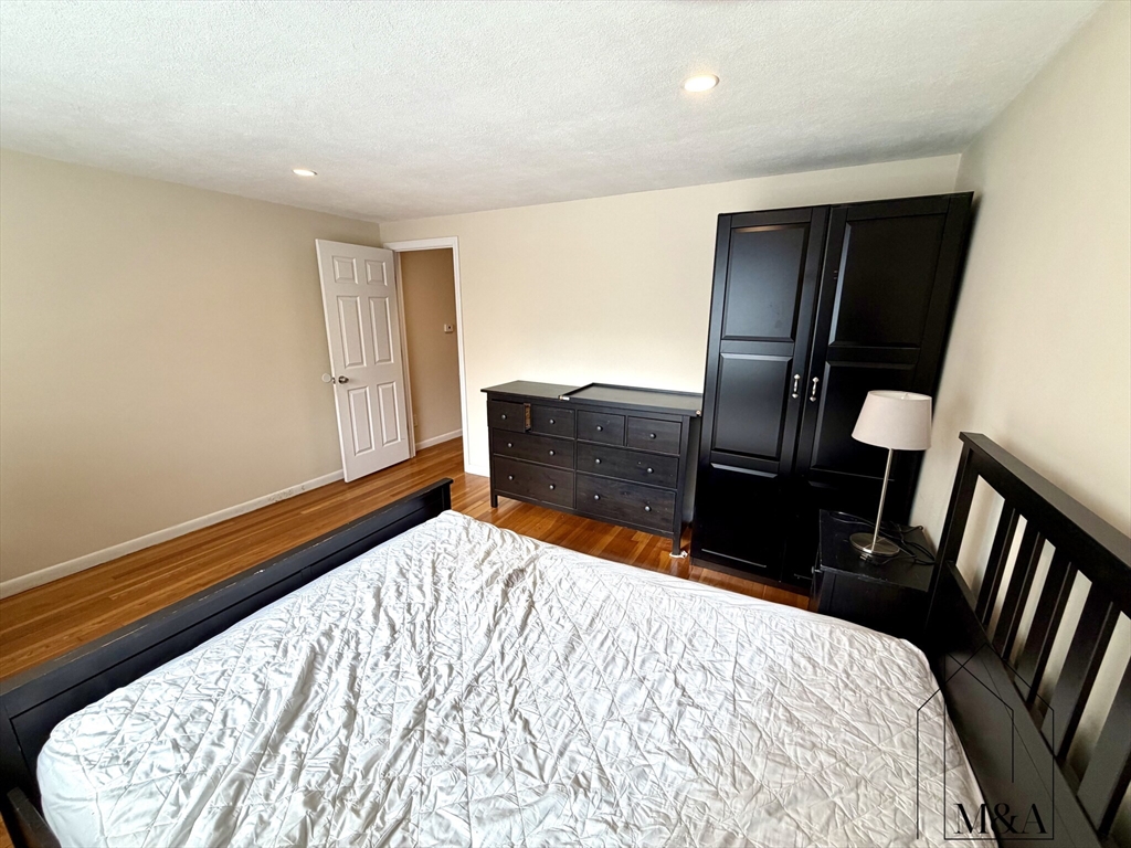 197 Kent Street, Unit 15 Brookline, MA 02446 - Photo 6 of 10 a bedroom with a bed and wooden floor