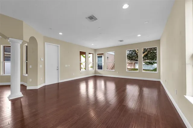 a view of empty room with wooden floor and fan