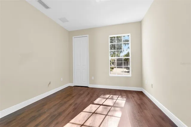 an empty room with wooden floor and windows