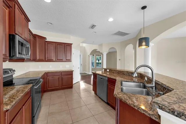 a kitchen with stainless steel appliances granite countertop a sink a stove top oven a counter space and cabinets