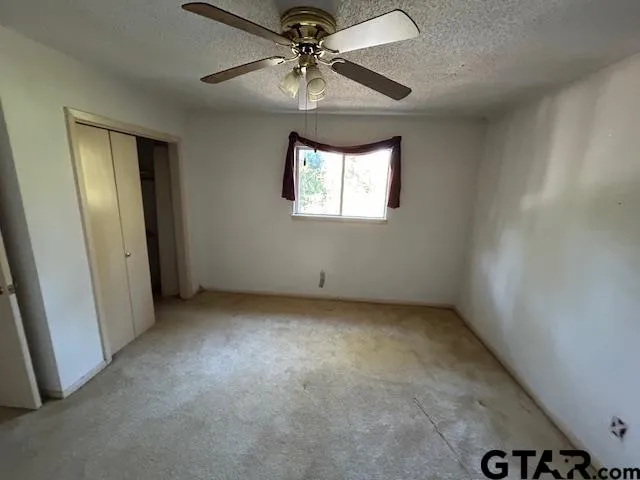 an empty room with a window and a fan
