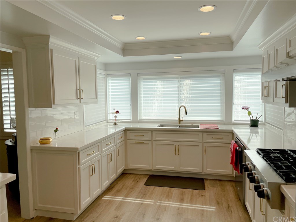 a large white kitchen with stainless steel appliances granite countertop a sink and a stove
