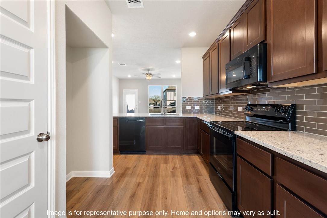 4787 Holm Oak Road Bryan, TX 77845 - Photo 5 of 12 a kitchen with stainless steel appliances granite countertop a sink a stove top oven a counter space and cabinets