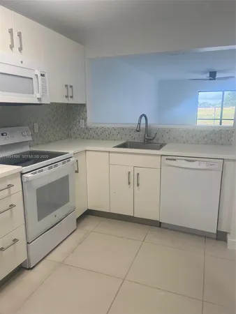 a kitchen with granite countertop a sink stove and cabinets