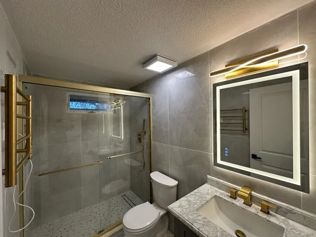 a bathroom with a granite countertop sink toilet and shower