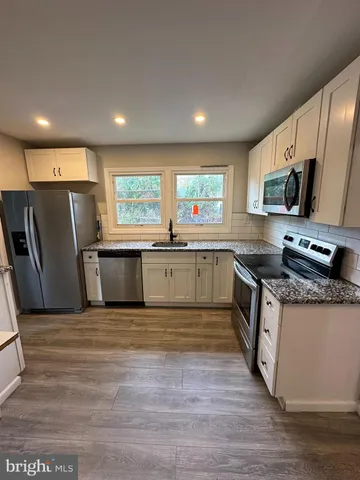 a large kitchen with stainless steel appliances granite countertop a stove a sink dishwasher a refrigerator and a microwave