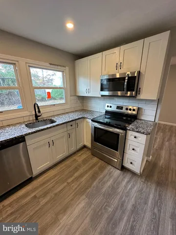 a large kitchen with stainless steel appliances granite countertop a stove a sink and a microwave