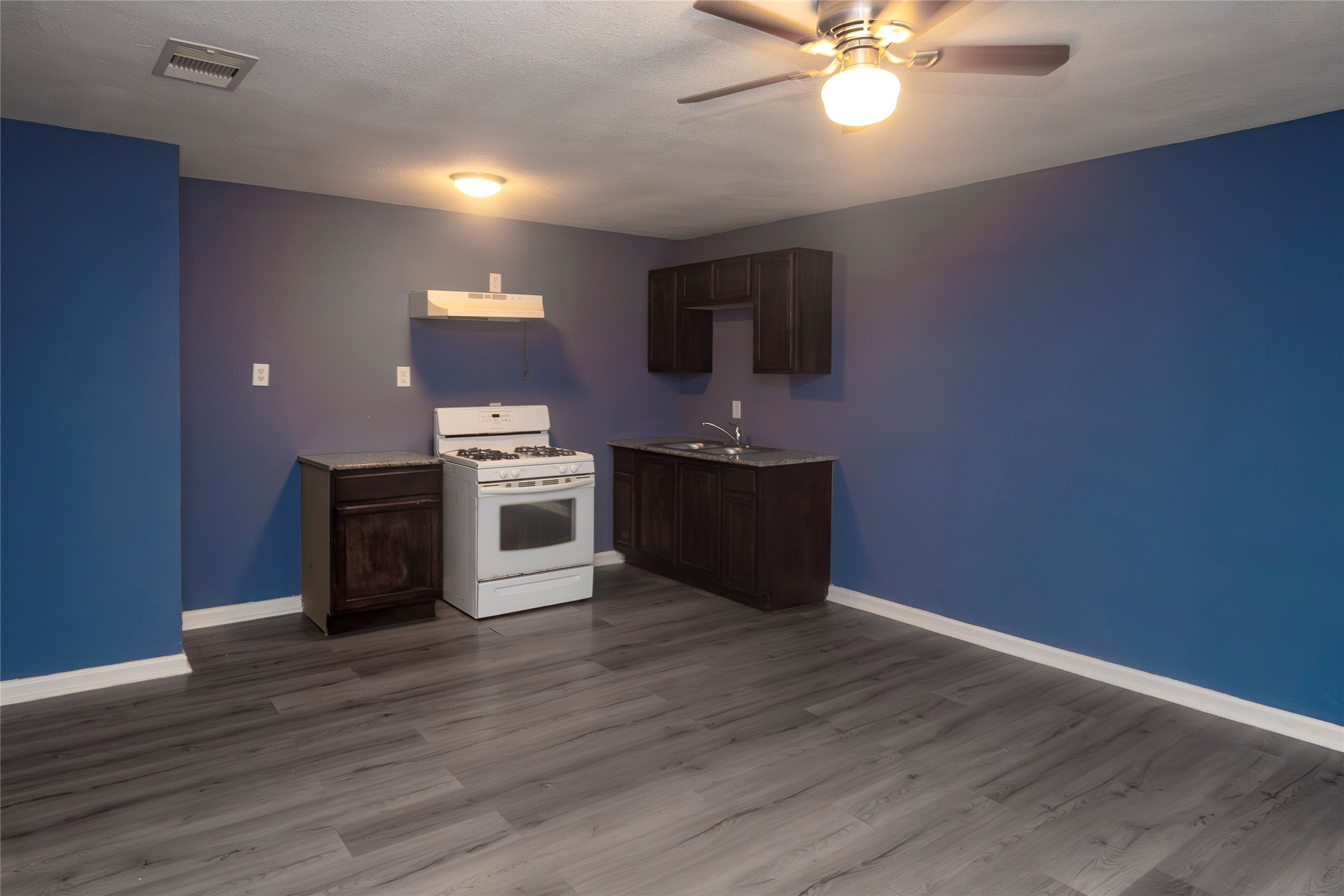716 Hargest Street, Unit B Prairie View, TX 77445 - Photo 2 of 11 a view of a kitchen with a stove wooden floor and a ceiling fan