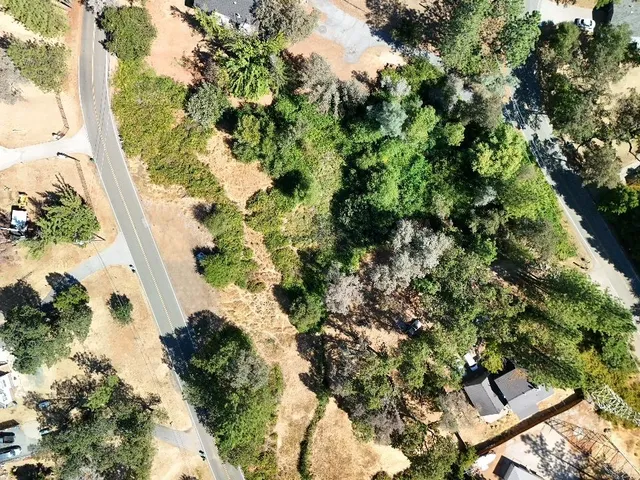an aerial view of residential house with outdoor space and trees all around