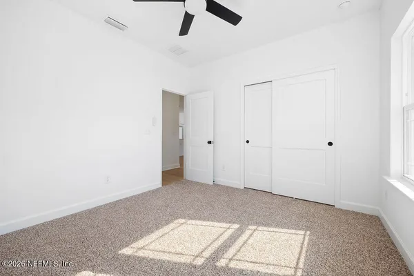 an empty room with ceiling fan and window