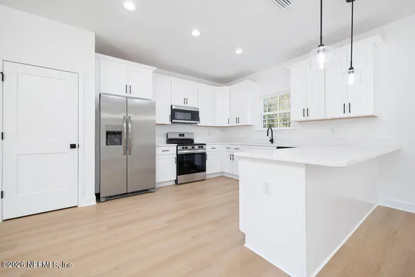 a kitchen with kitchen island white cabinets and stainless steel appliances