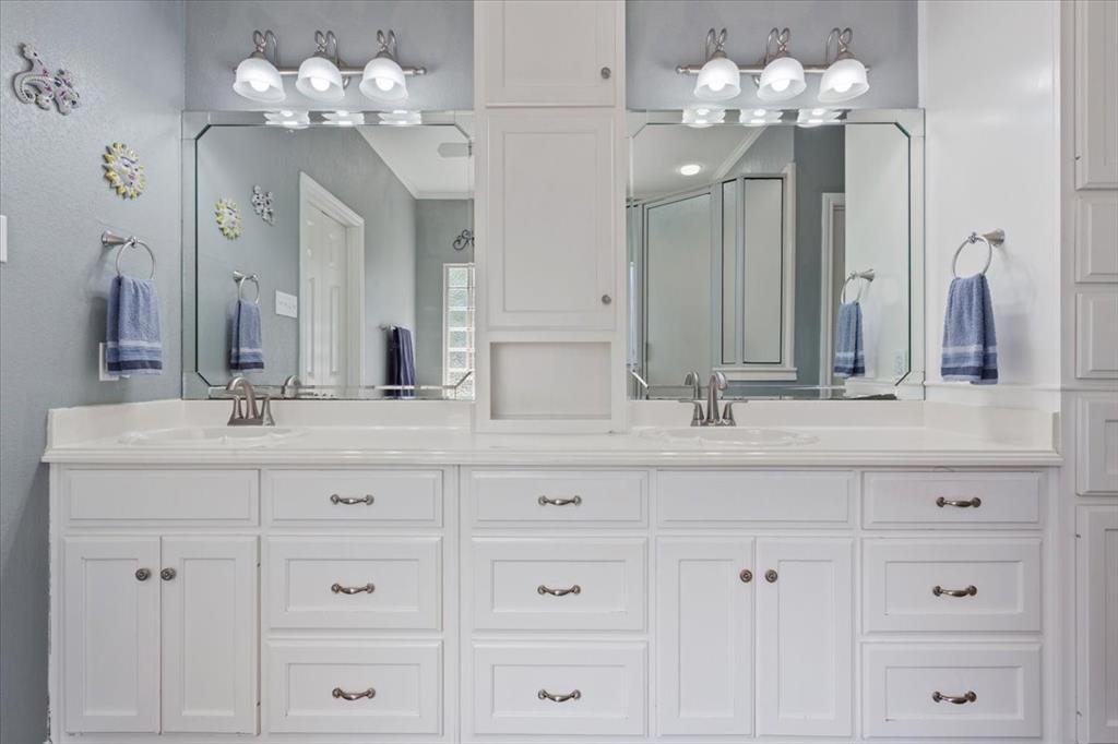 111 Spring Creek Street Waco, TX 76705 - Photo 21 of 40 Dual vanity with integrated sinks, expansive countertop, white cabinetry with silver-tone hardware, and two framed mirrors with overhead lighting