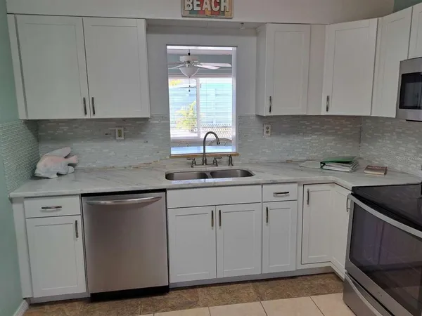a kitchen with white cabinets appliances a sink and a window