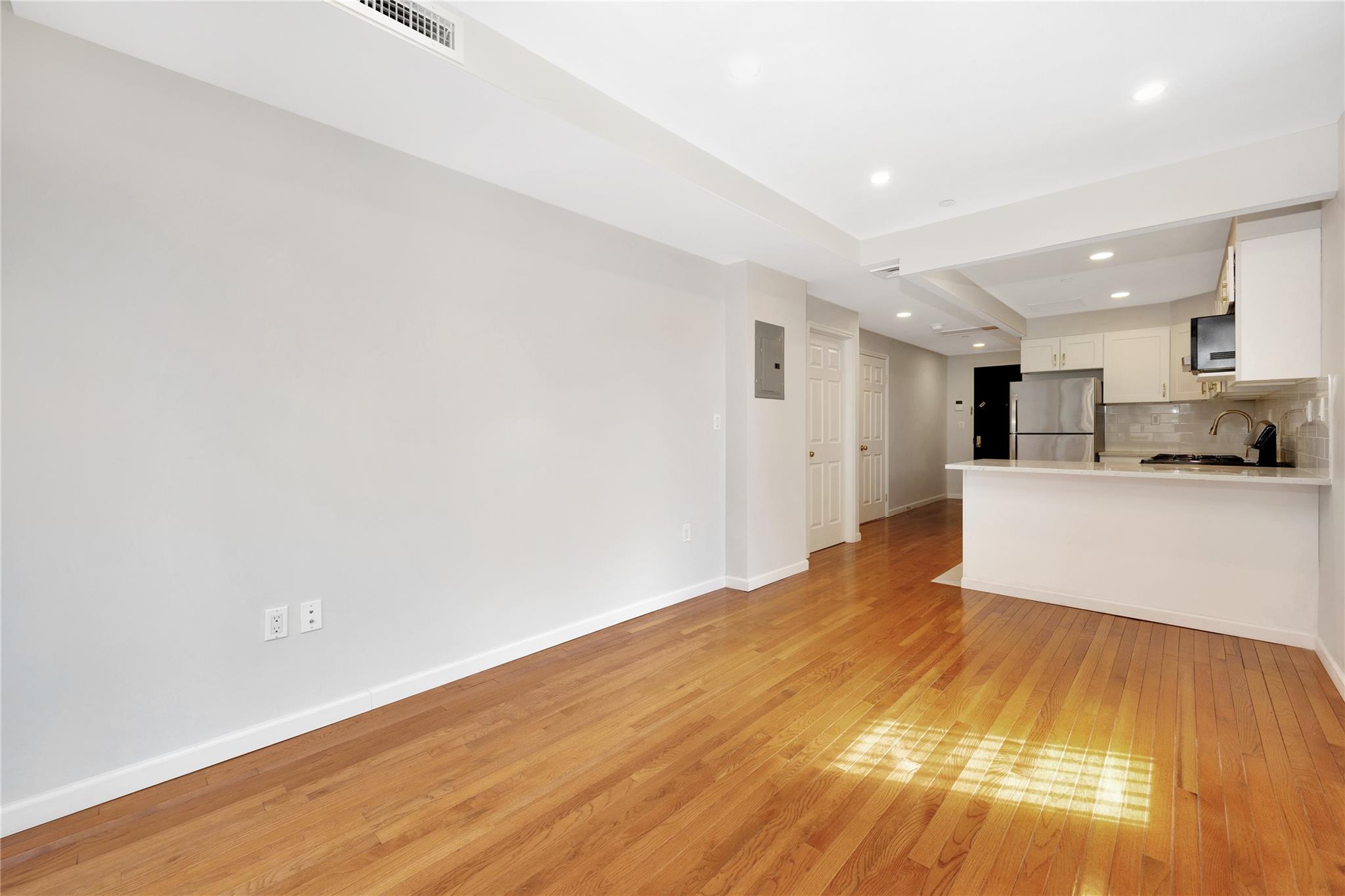 148-36 89th Avenue, Unit 3C Queens, NY 11435 - Photo 13 of 27 Kitchen with tasteful backsplash, white cabinetry, freestanding refrigerator, light wood-style floors, and a sink