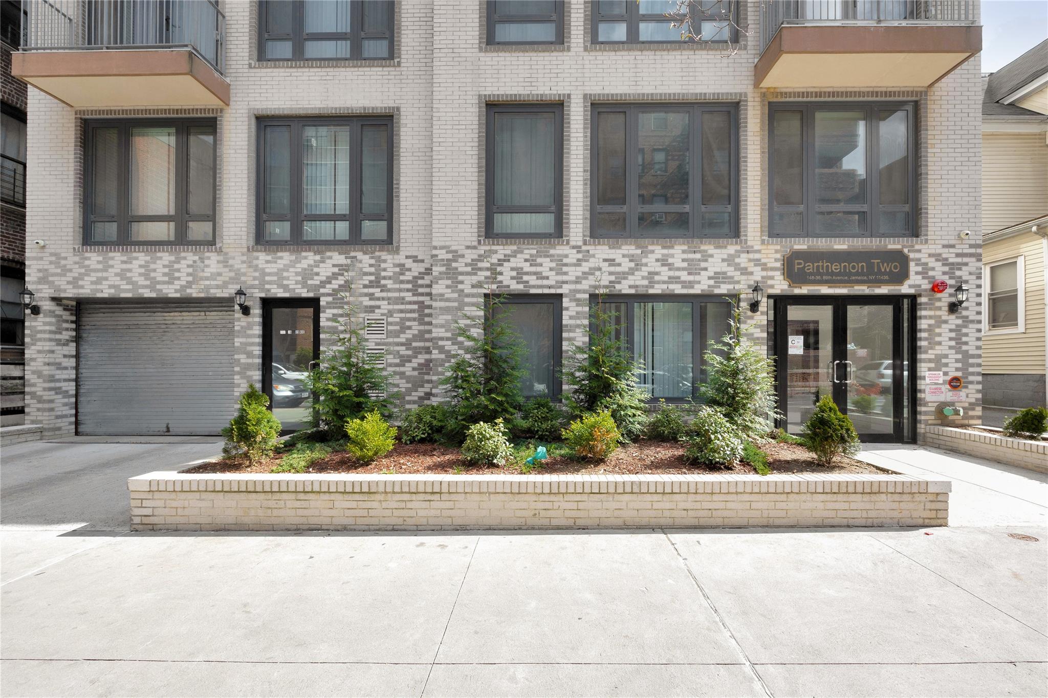 148-36 89th Avenue, Unit 3C Queens, NY 11435 - Photo 25 of 27 View of property with brick siding, driveway, and a garage