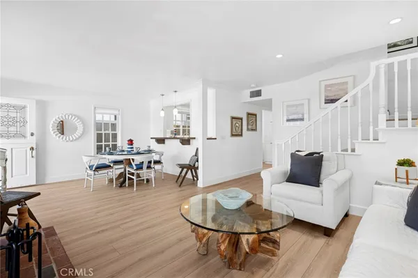 a living room with furniture and a dining table with wooden floor