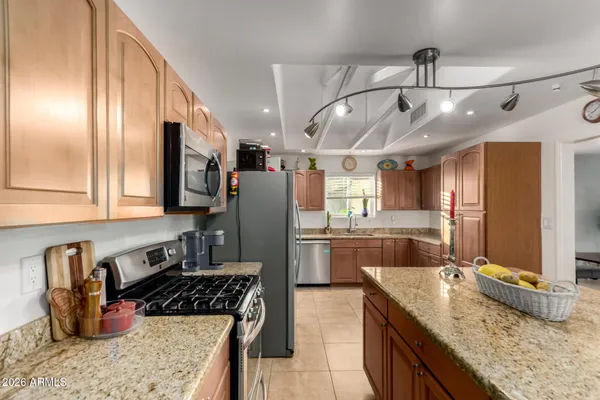 a kitchen with stainless steel appliances granite countertop a sink refrigerator and cabinets