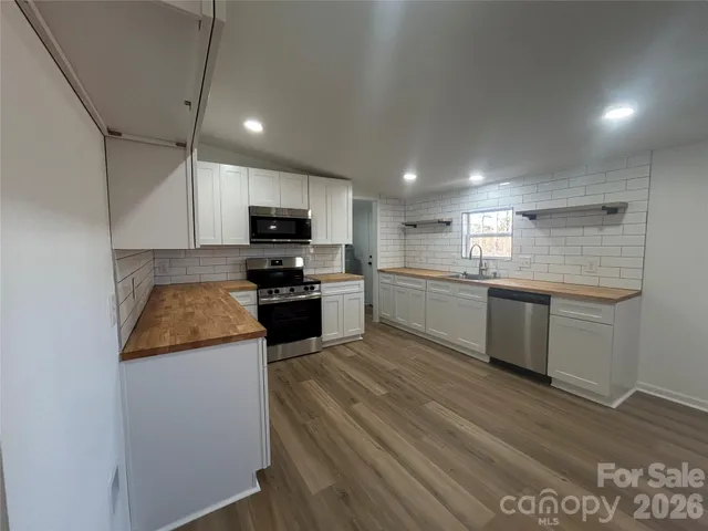a kitchen with granite countertop a sink a counter top space stainless steel appliances and cabinets