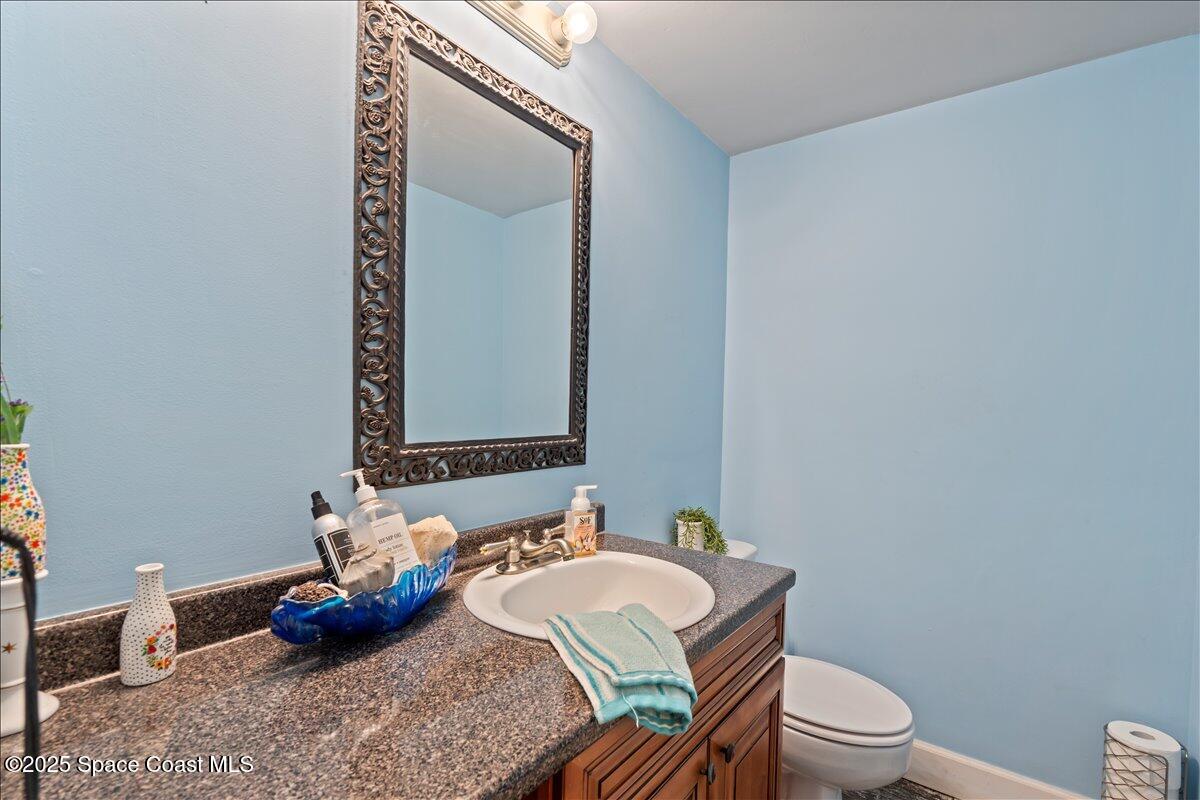 199 Florida A1A, Unit D201 Satellite Beach, FL 32937 - Photo 30 of 39 a bathroom with a granite countertop toilet and a mirror