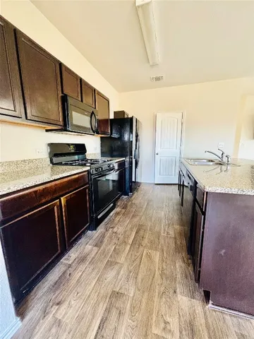 a kitchen with stainless steel appliances granite countertop a stove a sink and a microwave