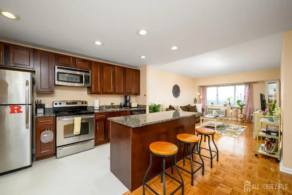 a kitchen with stainless steel appliances granite countertop a stove top oven a sink dishwasher a dining table and chairs with wooden floor