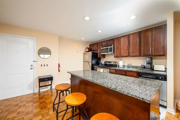 a kitchen with stainless steel appliances granite countertop a stove a sink a microwave a refrigerator and cabinets