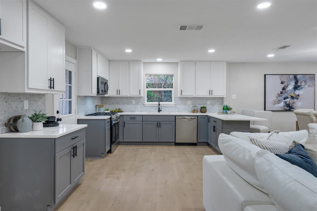 4815 Kelman Street Dallas, TX 75214 - Photo 10 of 37 Open-concept kitchen featuring two-tone cabinetry, light-toned wood-finish flooring, recessed lighting, and a full tile backsplash