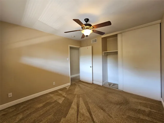 a view of a big room with wooden floor and a ceiling fan
