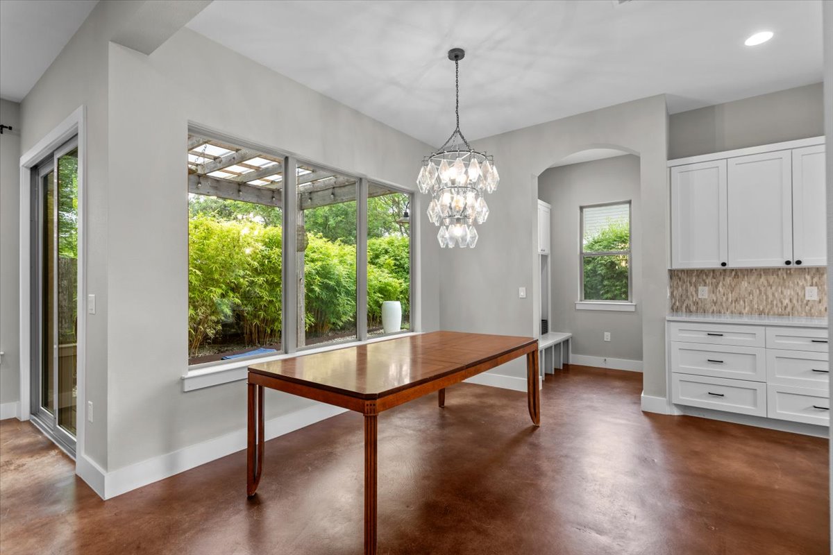 913 Stobaugh Street, Unit B Austin, TX 78757 - Photo 14 of 40 A refined dining space features a statement chandelier and a picturesque view of lush outdoor greenery. (Note: dining table will be removed)