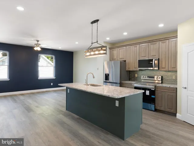 a kitchen with kitchen island granite countertop stainless steel appliances a stove sink microwave and cabinets