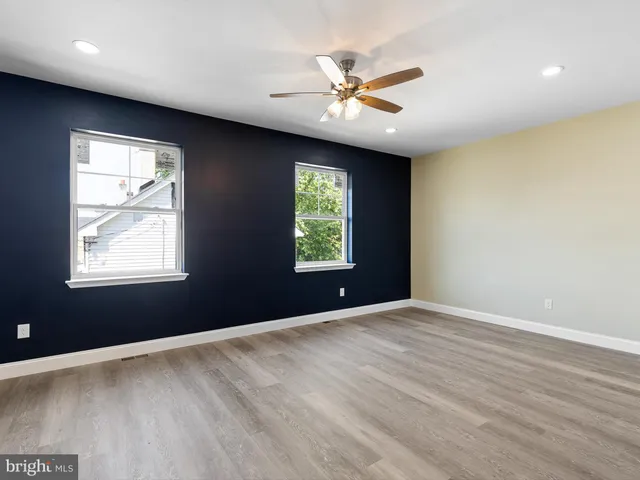 a view of an empty room with window and wooden floor