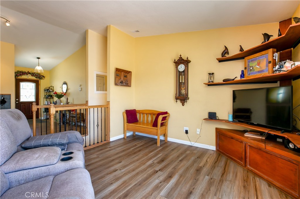 10960 Steinhoff Road Frazier Park, CA 93225 - Photo 22 of 46 The welcoming living room boasts an open feel with impressive vaulted ceilings and beautiful wood-look flooring. Warm-toned walls complement a large built-in media center and shelving unit, while a decorative wooden railing opens up to the neighboring dining area and entryway.
