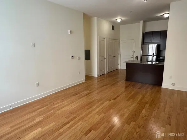 a view of kitchen and empty room with wooden floor
