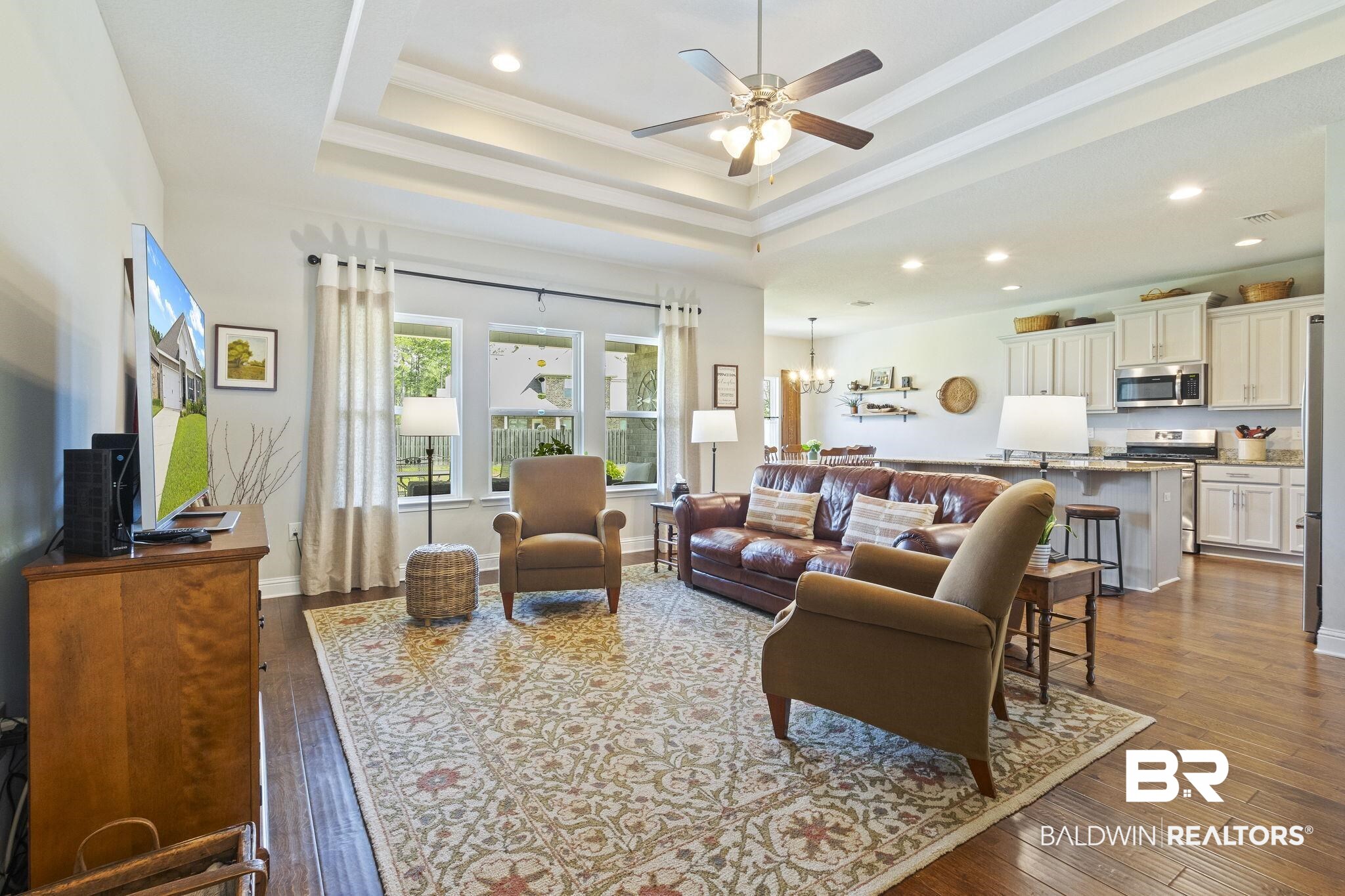 31663 Kestrel Loop Daphne, AL 36527 - Photo 15 of 86 Living room featuring ceiling fan with notable chandelier, hardwood / wood-style flooring, a raised ceiling, and ornamental molding