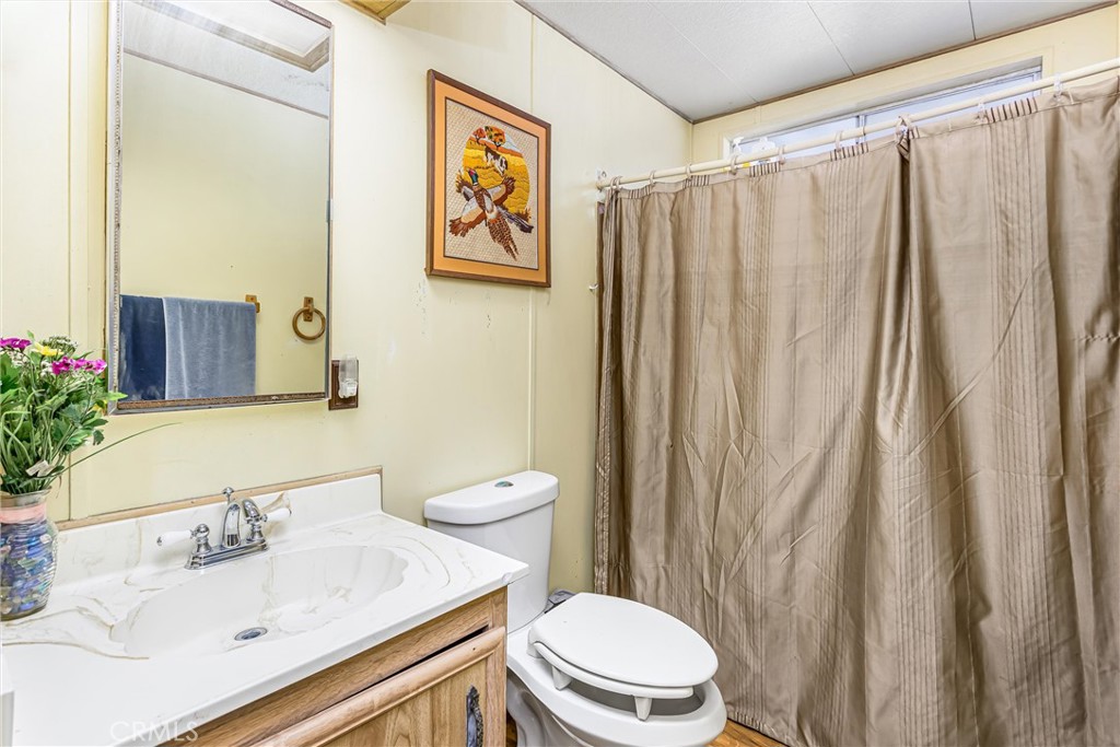 4000 Pierce Street, Unit 106 Riverside, CA 92505 - Photo 13 of 18 a bathroom with a sink a toilet and shower curtain