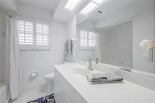 a bathroom with a granite countertop sink a toilet and a large mirror