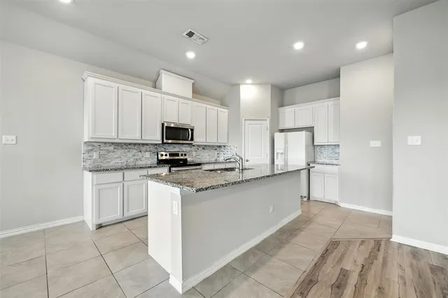 a kitchen with stainless steel appliances granite countertop a refrigerator and a stove top oven