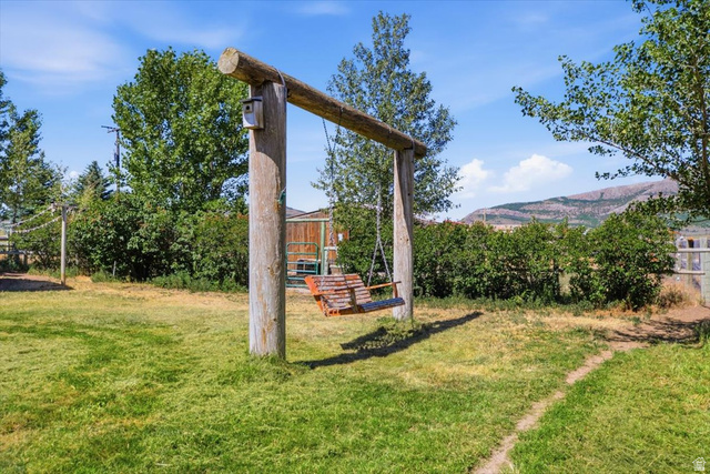 1634 West Arimo Road Arimo, ID 83214 - Photo 27 of 89 Expansive outdoor space featuring a rustic wooden swing set with a birdhouse, a path across the lawn, mature trees, and a mountain backdrop