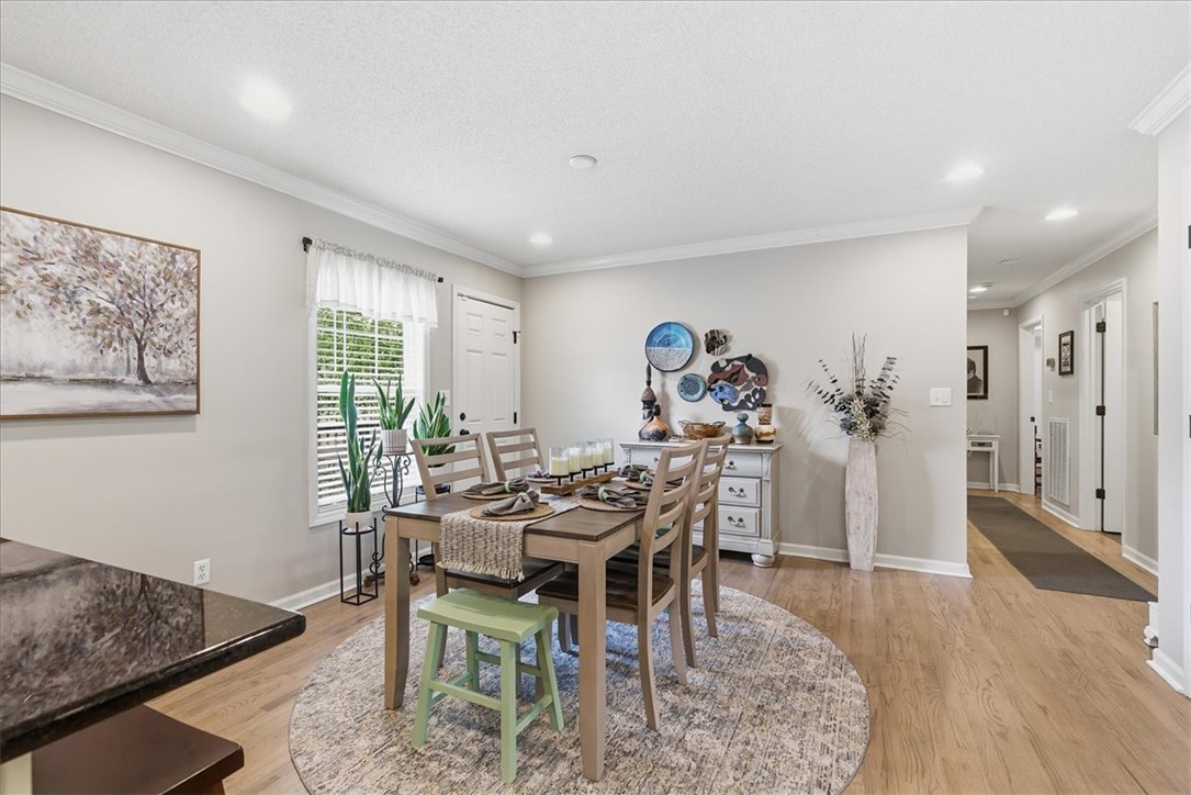 166 Amberwood Drive Anderson, SC 29621 - Photo 6 of 38 This bright dining area features warm flooring and elegant crown molding, creating an inviting atmosphere for meals.