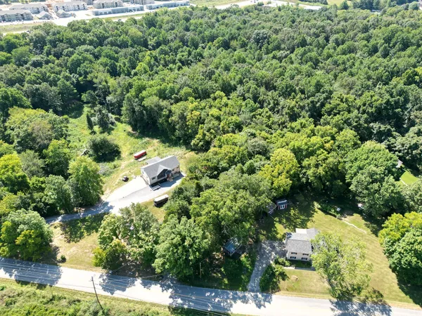 an aerial view of residential house with outdoor space and trees all around