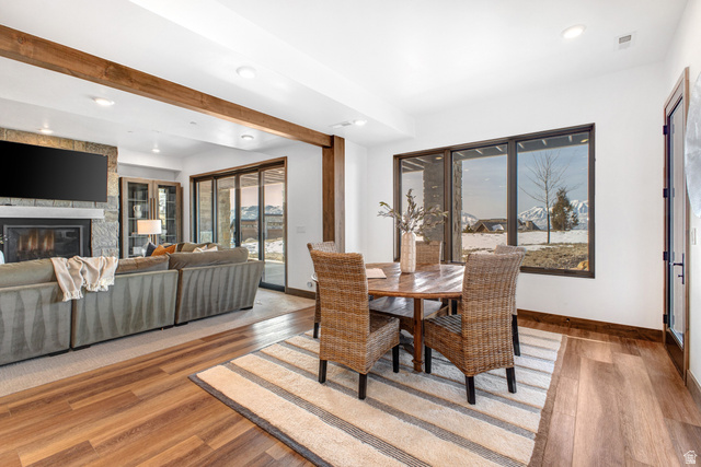 1282 Chimney Rock Road, Unit 344 Heber City, UT 84032 - Photo 34 of 55 Open-concept living space featuring wood-finish flooring, exposed ceiling beams, a stone-clad fireplace, and expansive windows with mountain scenery