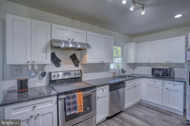 a kitchen with stainless steel appliances granite countertop a sink stove and cabinets