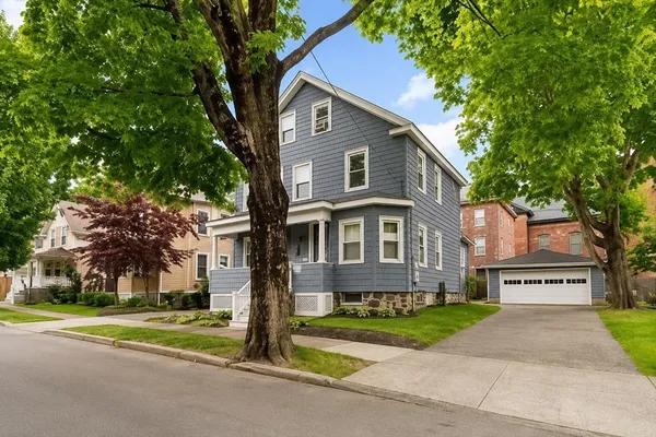 a front view of a house with a yard and trees
