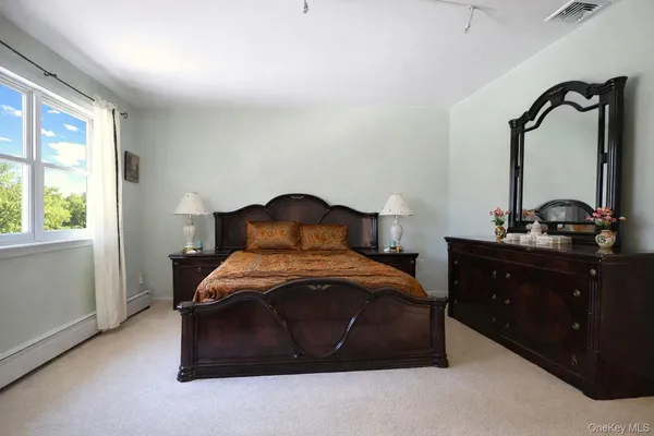 a bedroom with a bed and a mirror on dresser