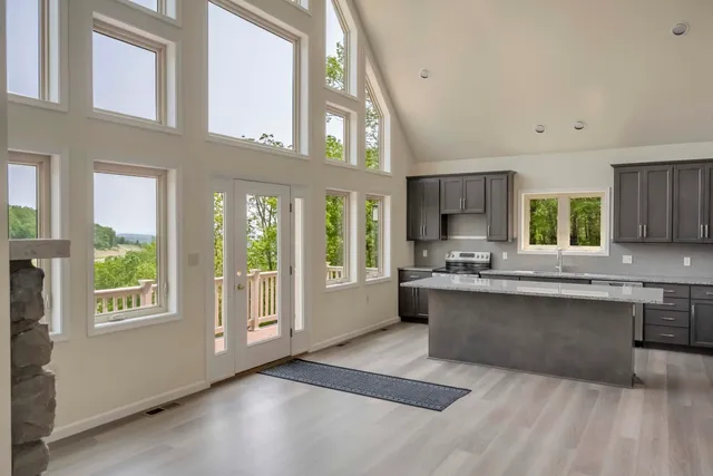 a large white kitchen with kitchen island granite countertop a large window