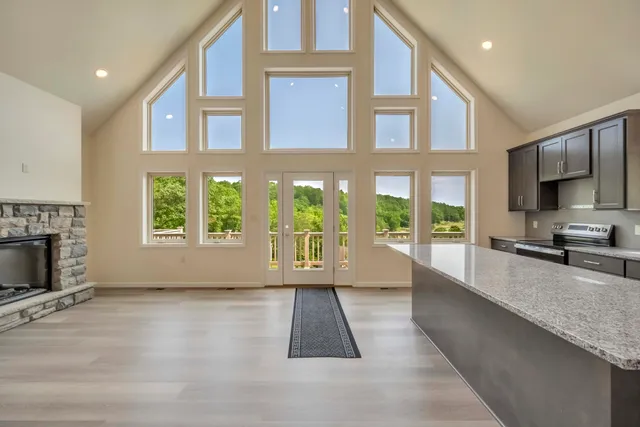 a kitchen with kitchen island granite countertop a refrigerator oven a sink and a large window