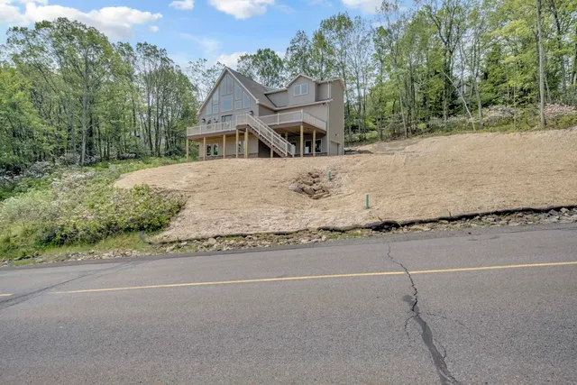 a view of a house with backyard and trees in the background